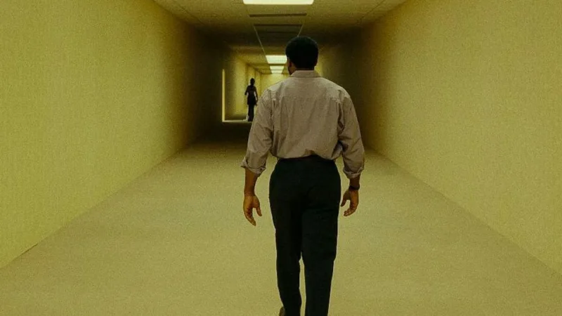 Un homme avance dans un couloir jaune sans fin dans Backrooms