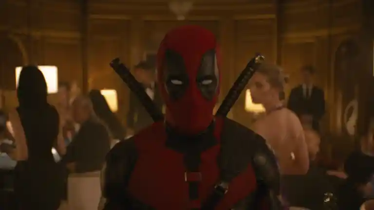 Deadpool en costume rouge au premier plan d’une réception dans Deadpool & Wolverine
