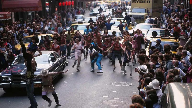 Des élèves de Fame dansent au milieu d'une rue de New York entourés par la foule