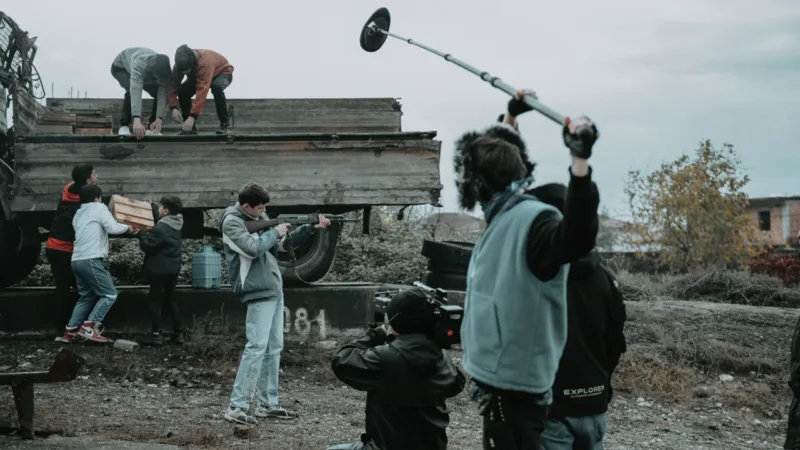 Équipe technique réunie pendant un tournage audiovisuel en extérieur