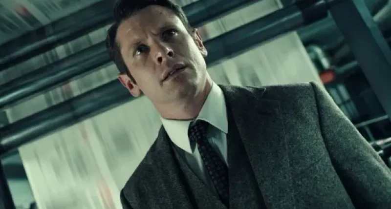 Jack O’Connell en costume dans le rôle du rédacteur Larry Lamb au milieu des presses