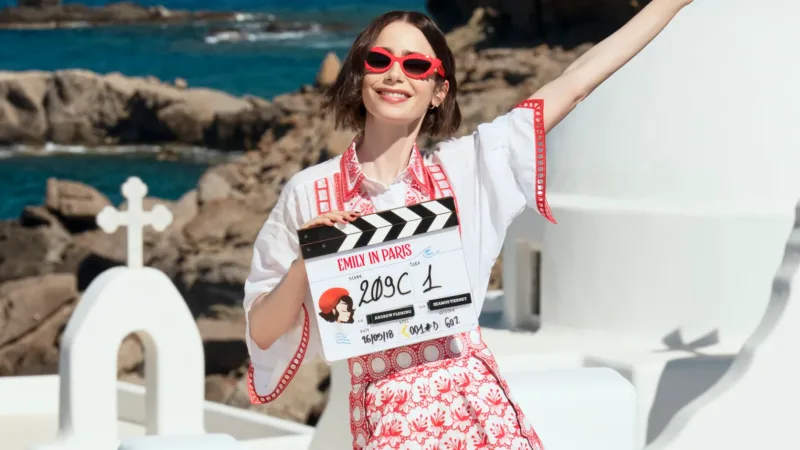 Lily Collins tient le clap du tournage d’Emily in Paris saison 6 face à la mer en Grèce