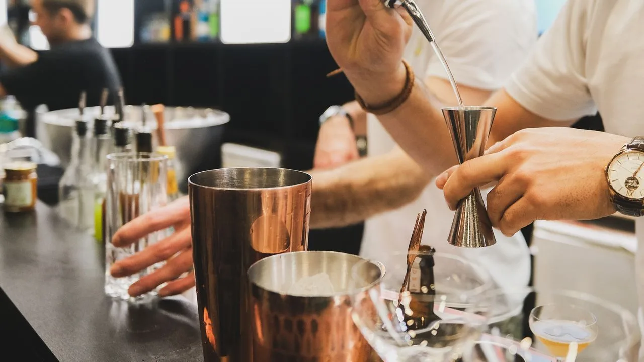 Bartender utilisant un doseur pour préparer un cocktail dans un bar
