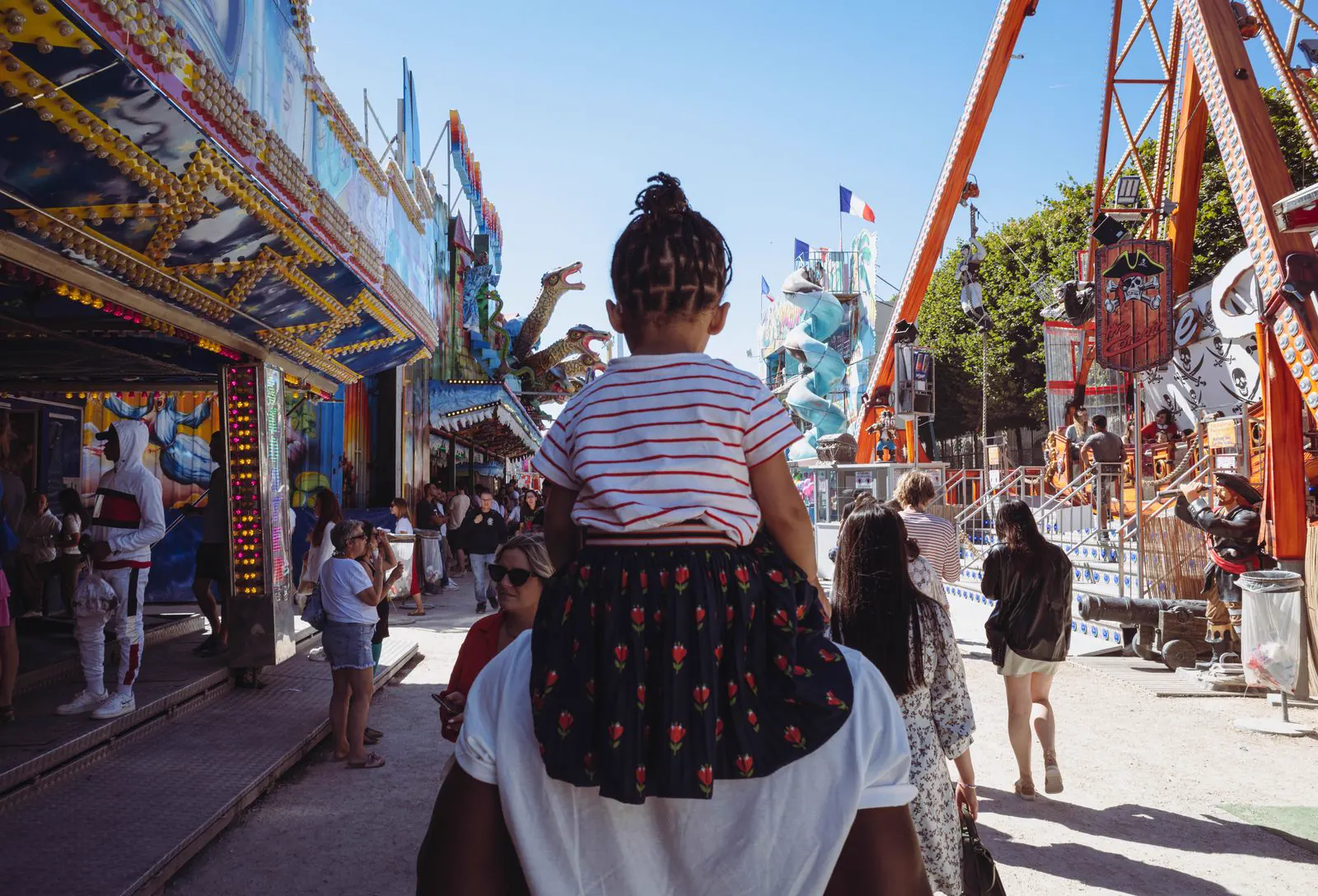 Père portant sa fille dans une fête foraine pour illustrer un casting familial