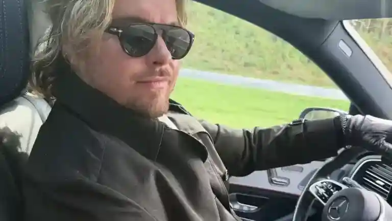 Homme blond au volant d’une voiture haut de gamme
