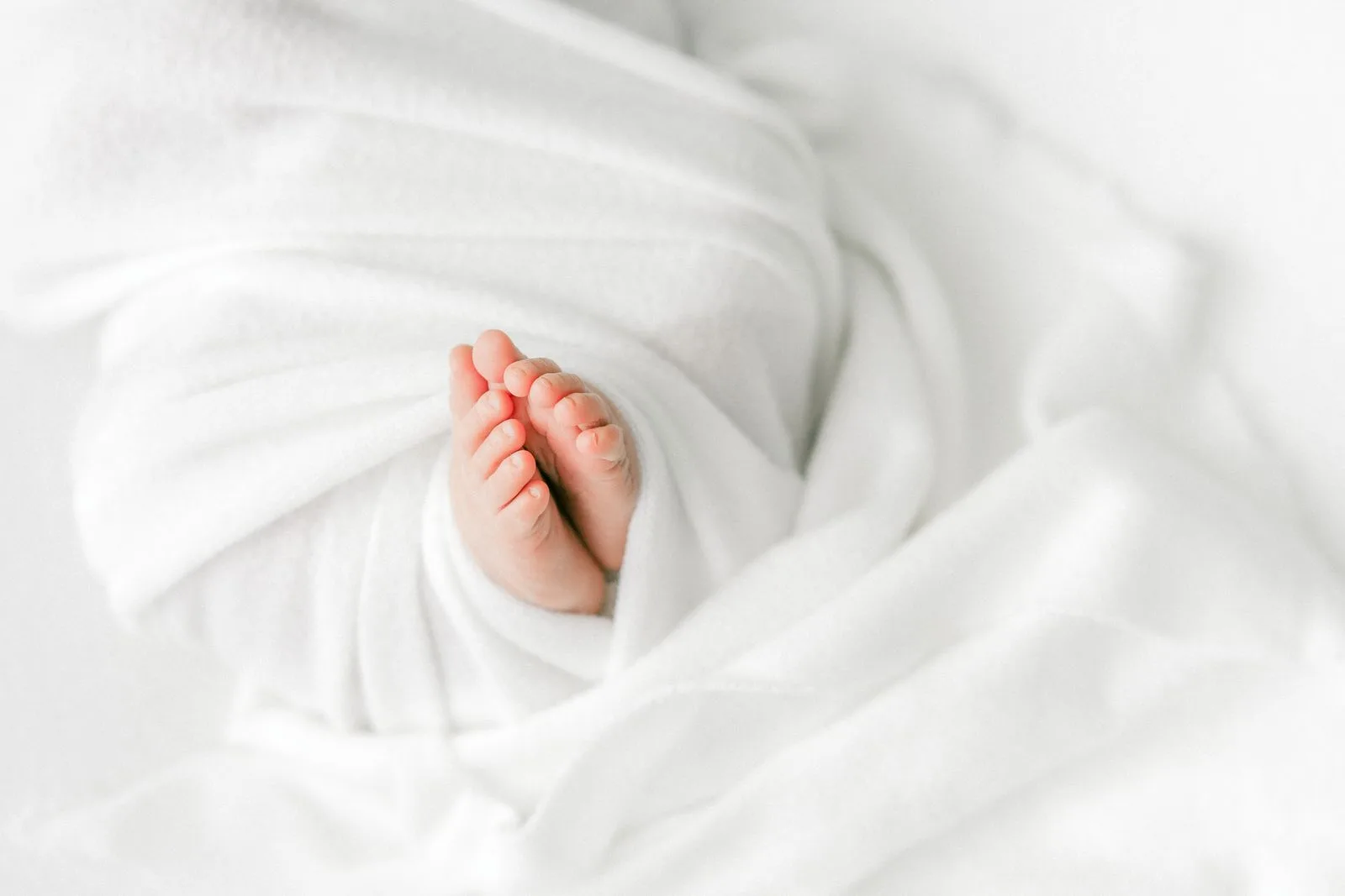 Pieds d'un nourrisson emmailloté dans une couverture blanche
