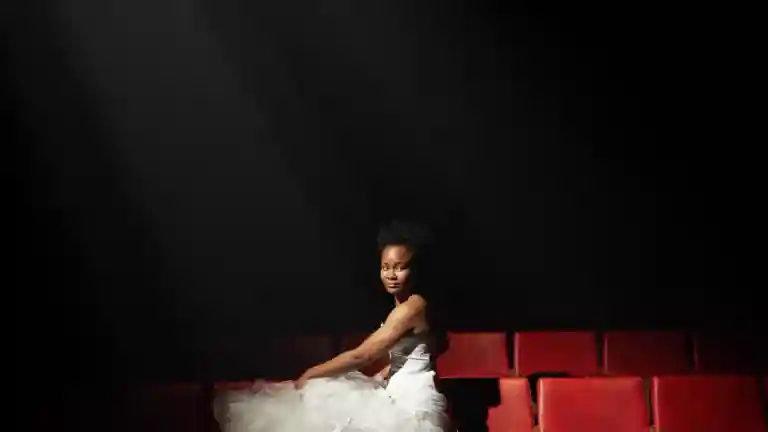 Femme assise dans une salle de théâtre sous un projecteur