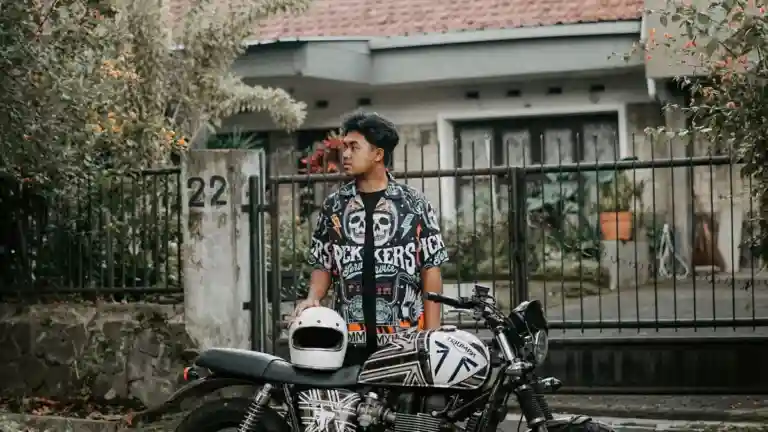 Homme tenant un casque à côté d’une moto dans une rue