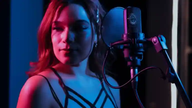 Chanteuse devant un microphone dans un studio éclairé de bleu et rose, image illustrative