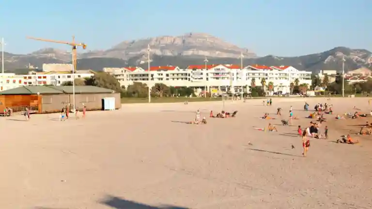 Plage du Prado à Marseille avec promeneurs et reliefs en arrière-plan