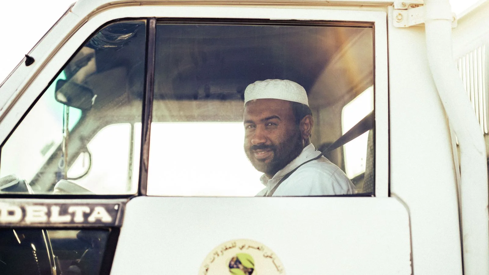 Un conducteur souriant est photographié dans la cabine d'un véhicule utilitaire, illustration