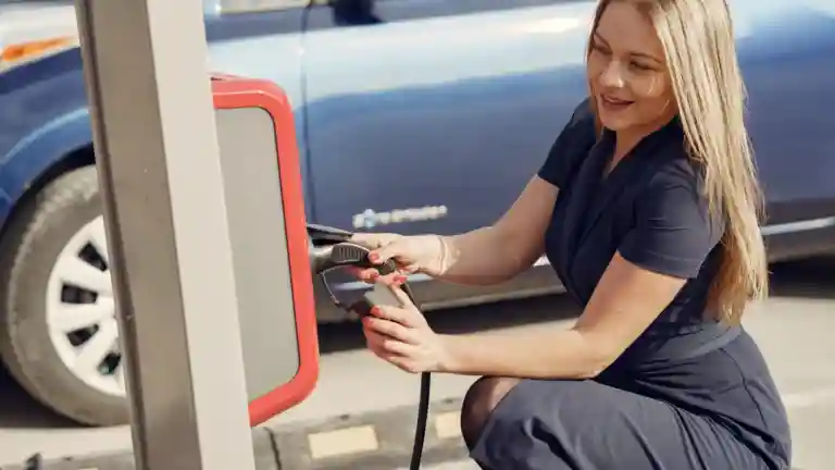 Une femme utilise une borne de recharge pour voiture électrique en extérieur