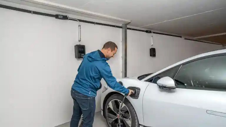 Un homme branche une voiture électrique sur une borne de recharge