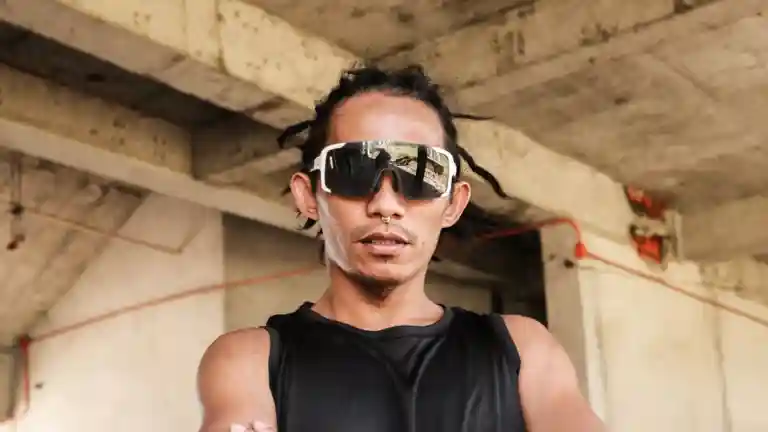Homme portant des lunettes de soleil et un haut noir, les bras croisés