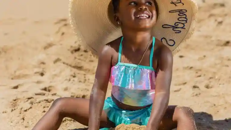 Jeune fille en maillot de bain assise sur une plage