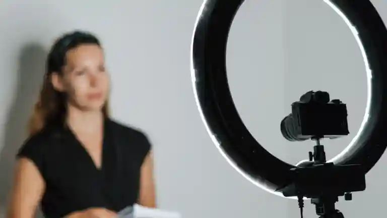 Une femme participe à un enregistrement vidéo devant une caméra et un éclairage circulaire