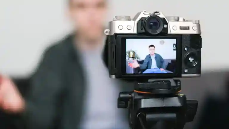 Un homme se filme devant une caméra fixée sur un trépied pour une vidéo en ligne