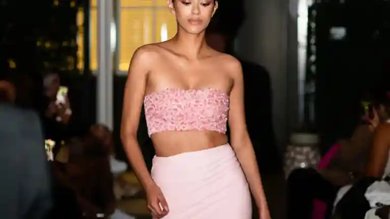 Une mannequin défile sur un podium en portant une tenue rose devant le public