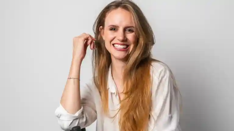 Portrait d’une femme souriante assise en tenue claire, photographie illustrative