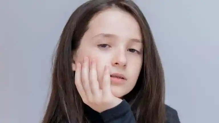 Portrait photographique d'une jeune fille aux cheveux longs portant un haut sombre, expression pensive