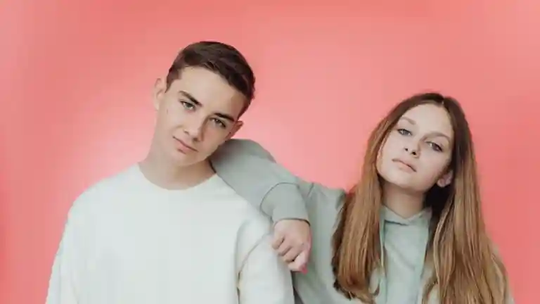Garçon et fille posant ensemble devant un fond rose en studio