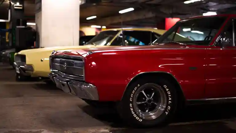 Deux voitures américaines anciennes, dont une Dodge rouge, photographiées dans un parking.