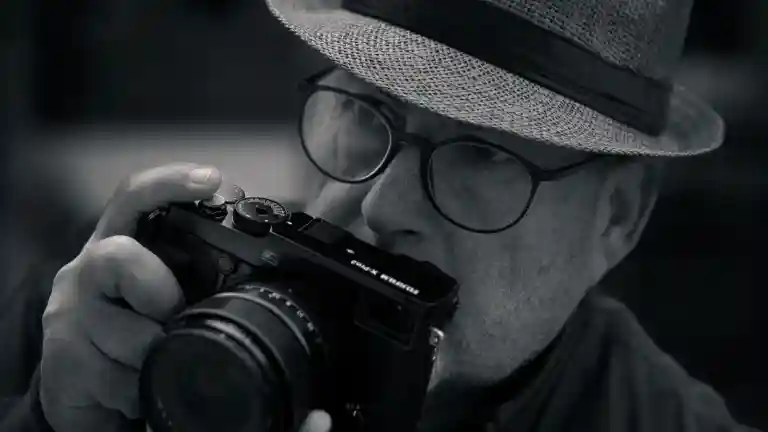 Un photographe au chapeau tient un appareil photo dans un portrait de style rétro, sans représenter Man Ray.