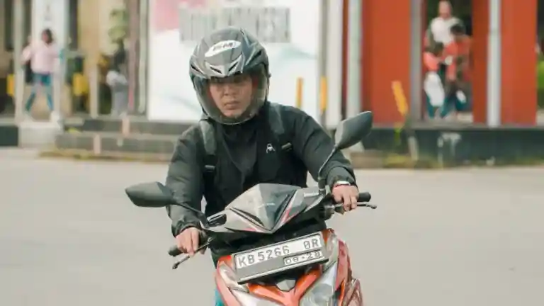 Homme casqué conduisant un scooter dans une rue urbaine