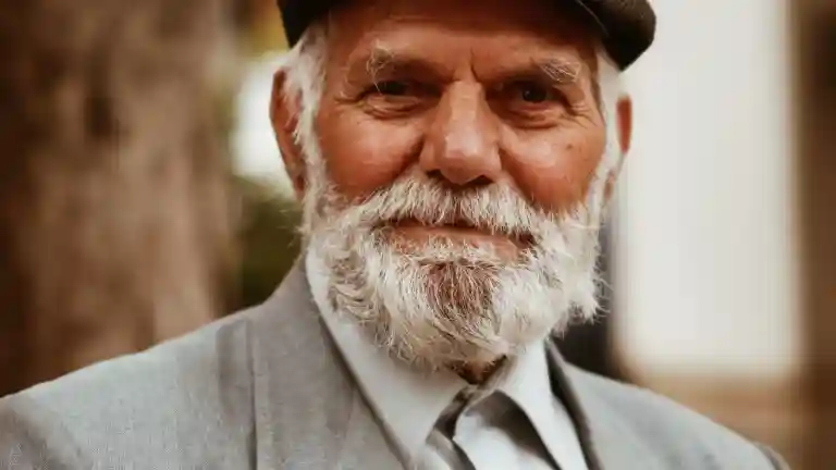 Un homme senior vêtu d’un costume clair et d’un chapeau, photographie illustrative.