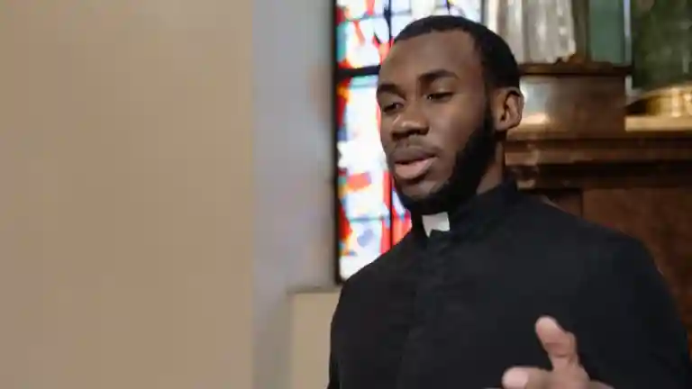 Prêtre en tenue noire à col blanc dans une église