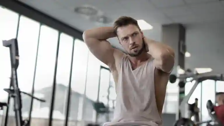 Un homme athlétique aux bras musclés prend une pose assurée dans une salle de sport.