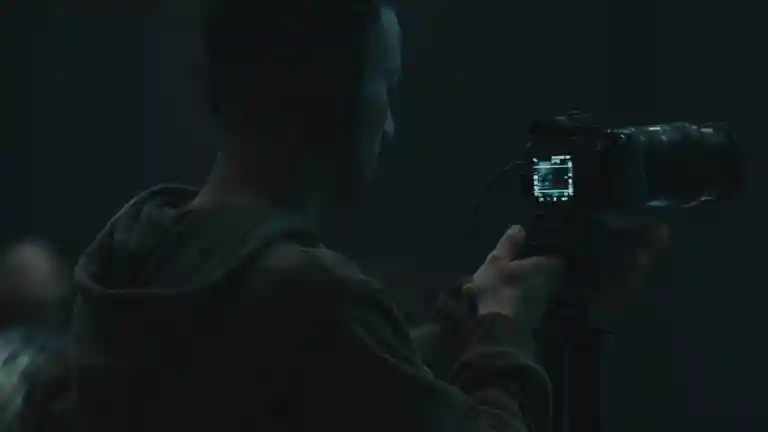 Une personne utilise une caméra vidéo dans une pièce sombre.