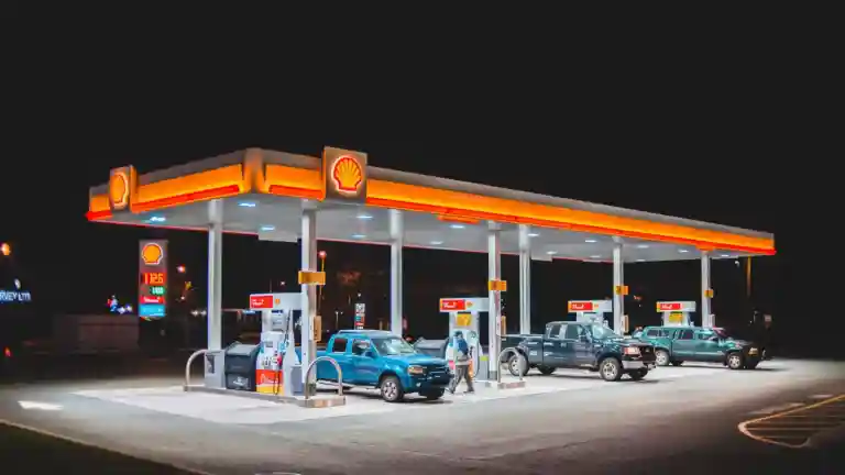 Voitures présentes dans une station-service éclairée (photographie d'illustration)