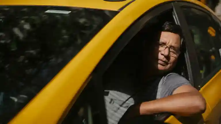 Un chauffeur de taxi assis à bord de son véhicule jaune en ville.