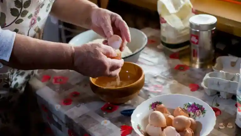 Mains d’une femme préparant des œufs dans une cuisine