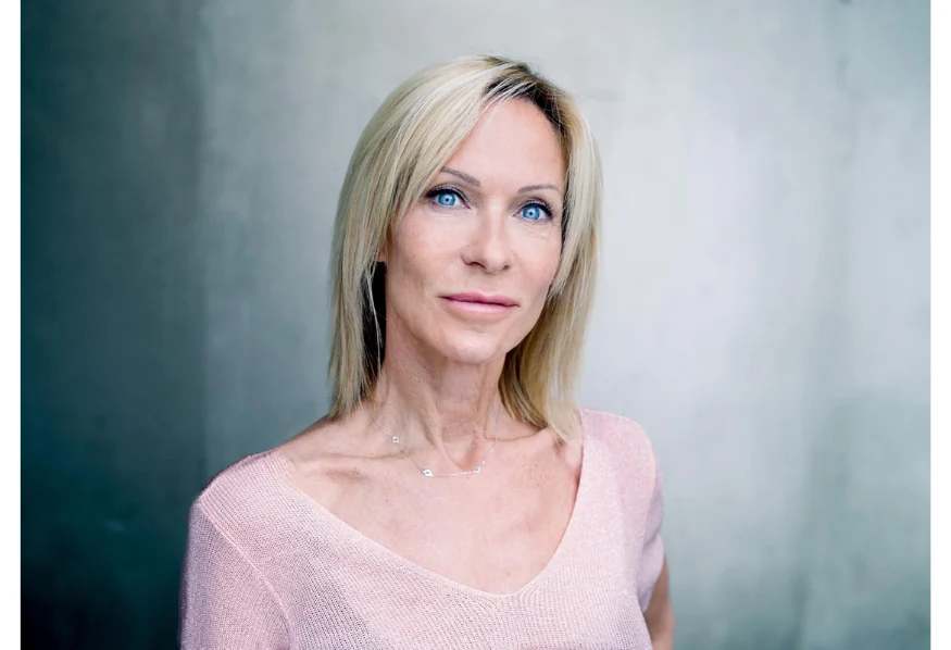 Portrait de Rebecca Hampton, cheveux blonds et haut rose devant un fond gris