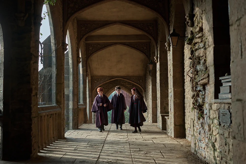 Harry, Ron et Hermione marchant sous les arches de Poudlard