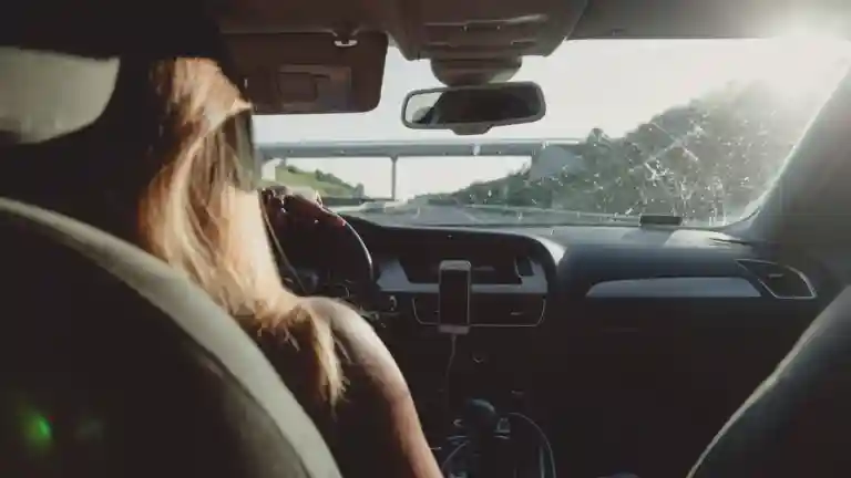 Femme au volant d’une voiture vue depuis la banquette arrière