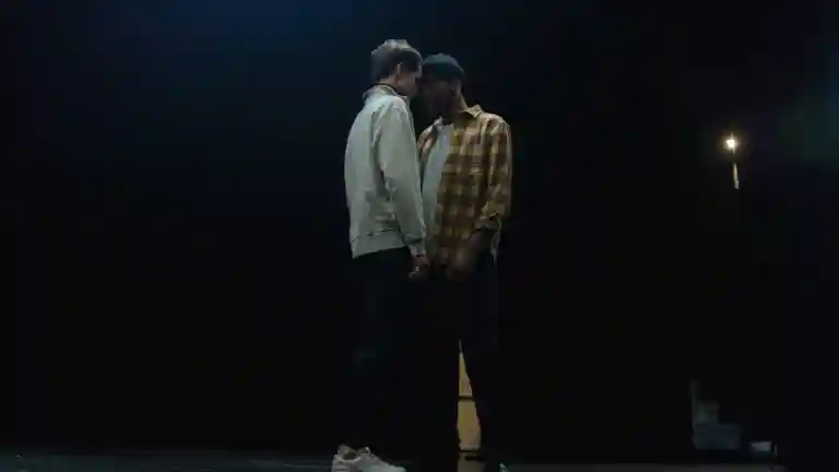 Deux comédiens répètent une scène sur une scène de théâtre sombre