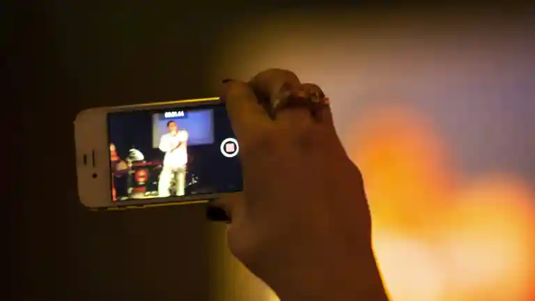 Une spectatrice photographie une prestation de scène à l’aide de son smartphone