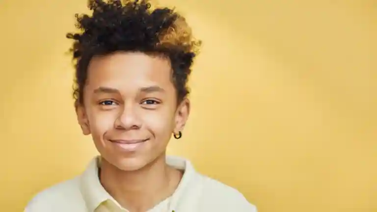 Portrait en studio d’un jeune garçon souriant aux cheveux bouclés sur fond jaune