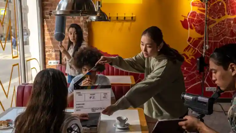 Équipe de tournage filmant une scène avec plusieurs personnes dans un décor