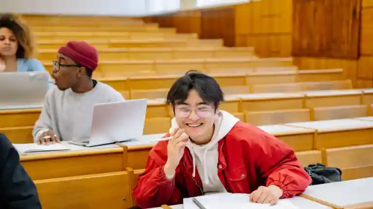 Étudiants majeurs échangeant et prenant des notes autour de tables