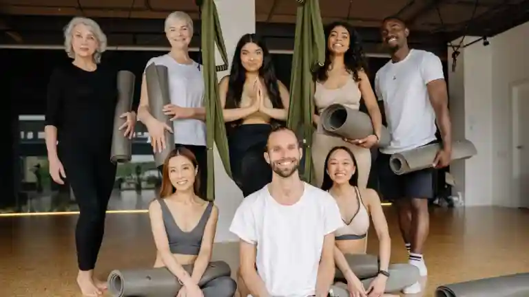 Groupe de femmes et d’hommes avec leurs tapis dans un studio de yoga
